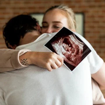 Glückliches Paar umarmt sich mit Ultraschallbild – Symbol für Begleitung in besonderen Lebensphasen wie Schwangerschaft und Elternschaft“